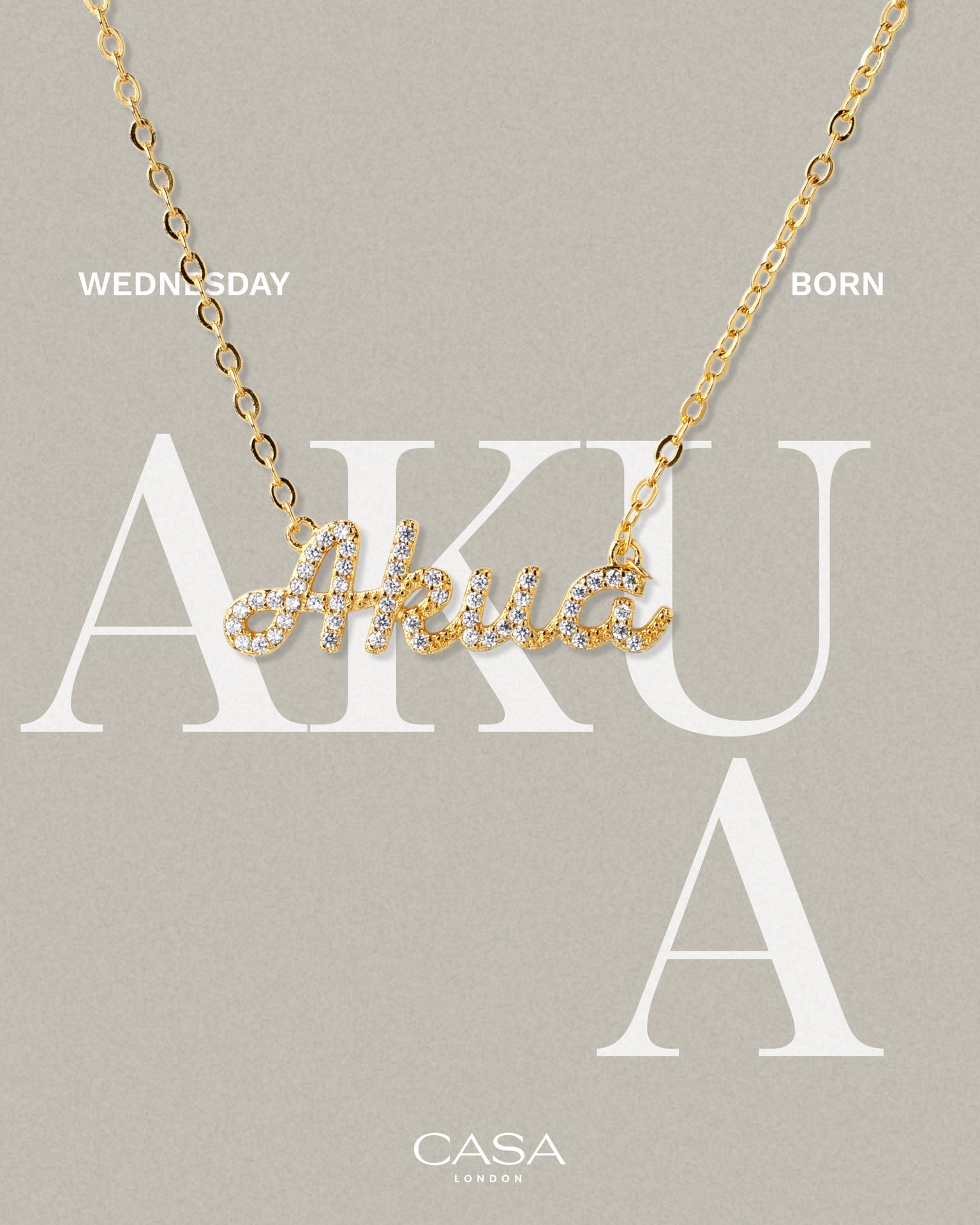 A product shot of CASA London’s 18k gold Akua Pavé Necklace. The delicate gold chain features a script pendant spelling "Akua," encrusted with shimmering pavé-set stones against a neutral, textured background. Overlaid text reads "WEDNESDAY BORN," highlighting the brand's commitment to celebrating cultural heritage and personal narratives through modern luxury.