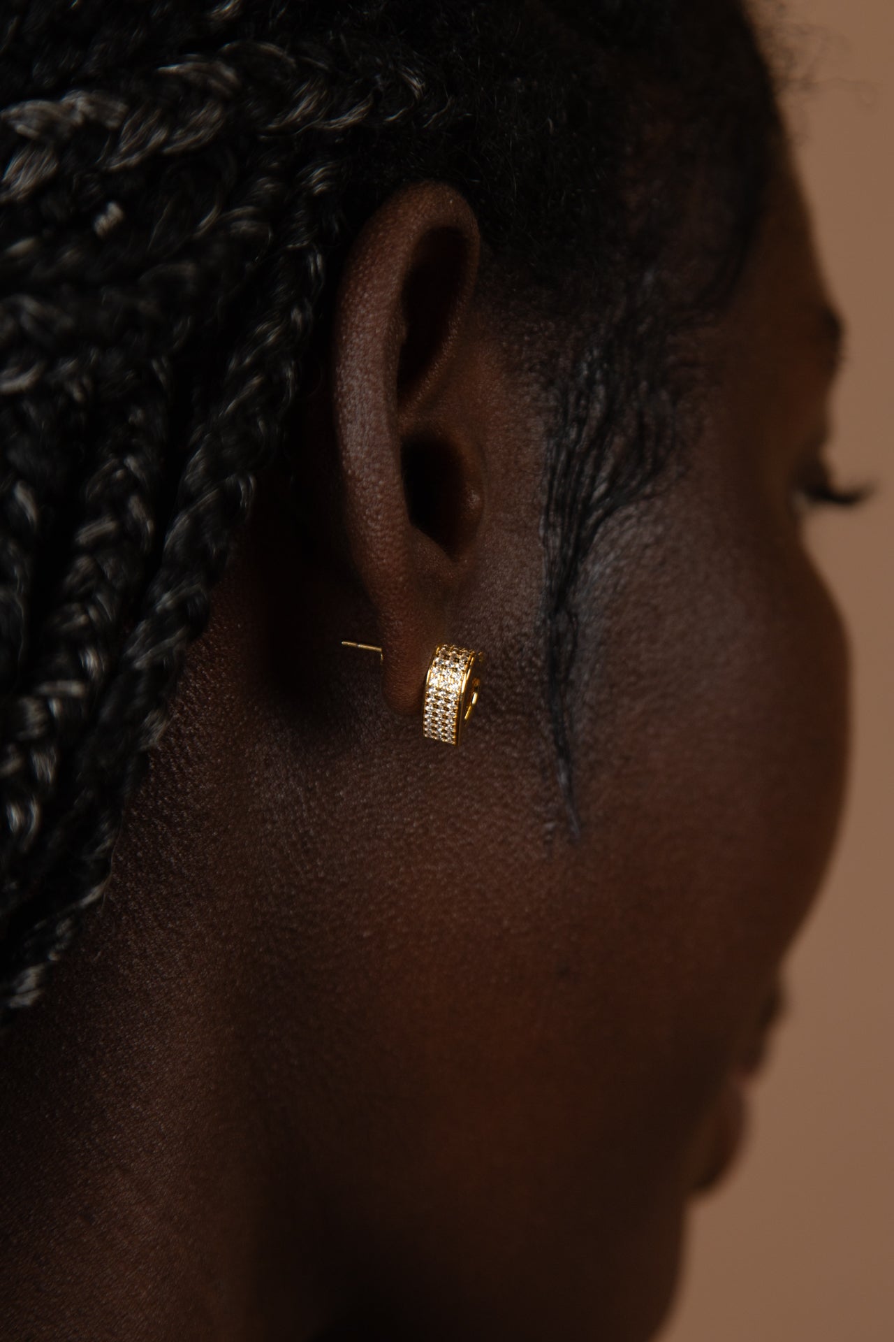 A close-up profile featuring the CASA London Akoma stud earring. The heart-shaped gold piece features a sophisticated hollow center and a pavé-set border of small, clear stones, showcasing a blend of traditional symbolism and modern luxury.