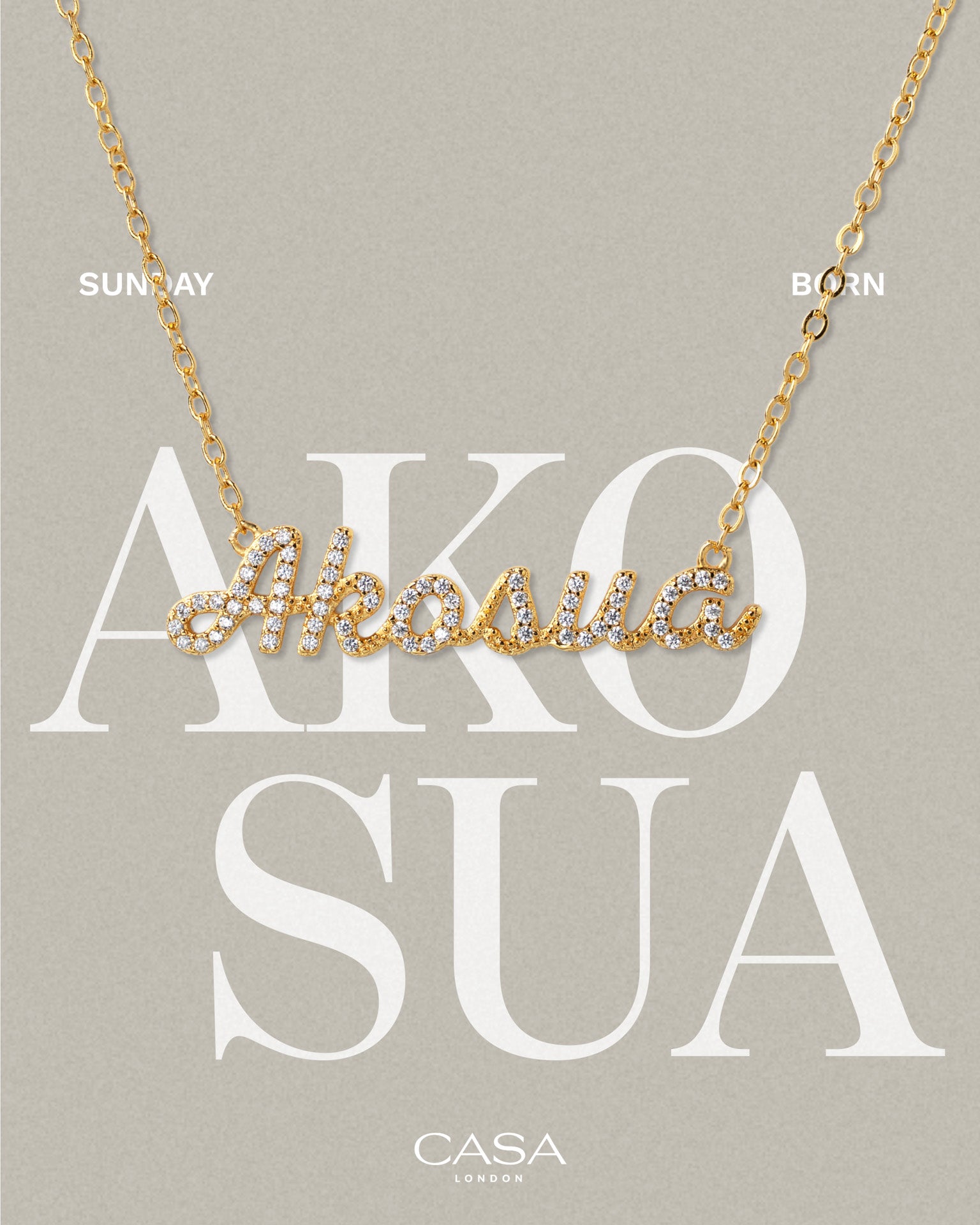 A product shot of CASA London’s 18k gold Akosua Pavé Necklace. The delicate gold chain features a script pendant spelling "Akosua," encrusted with shimmering pavé-set stones against a neutral, textured background. Overlaid text reads "SUNDAY BORN," highlighting the brand's commitment to celebrating cultural heritage and personal narratives through modern luxury.