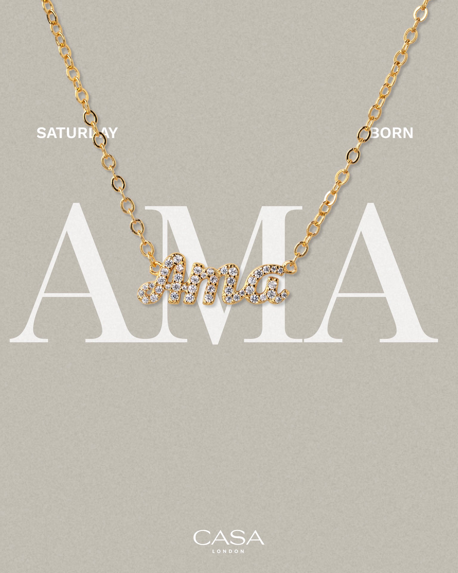 A product shot of CASA London’s 18k gold Ama Pavé Necklace. The delicate gold chain features a script pendant spelling "Ama," encrusted with shimmering pavé-set stones against a neutral, textured background. Overlaid text reads "SATURDAY BORN," highlighting the brand's commitment to celebrating cultural heritage and personal narratives through modern luxury.