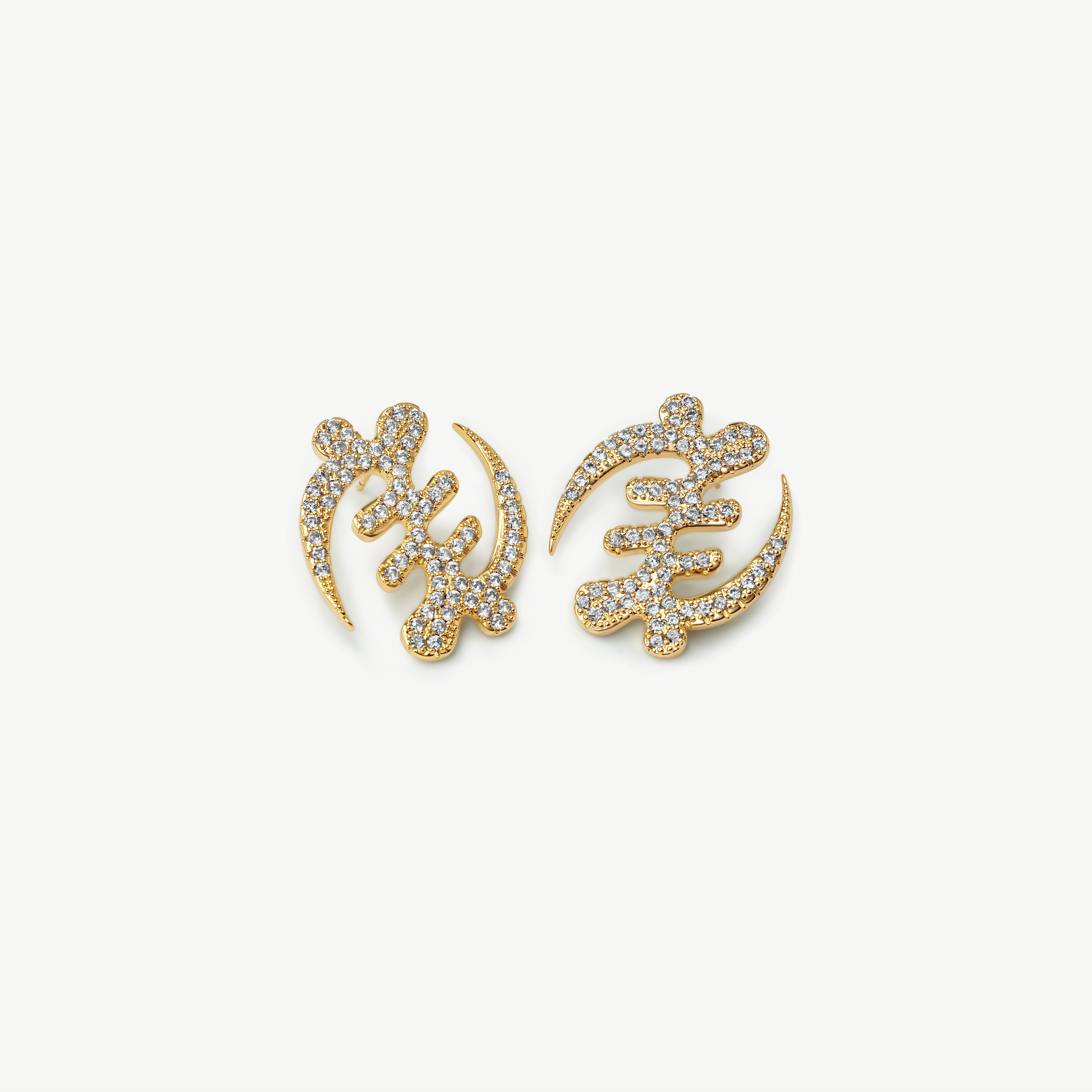 A high-resolution product shot of CASA London's 18k gold plated Gye Nyame Pavé oversized statement Earrings. The pair is shaped into the iconic Adinkra symbol, signifying the supremacy of God, and is intricately encrusted with shimmering pavé-set stones. Set against a minimalist white background, the design highlights the brand’s signature blend of cultural heritage and sophisticated modern luxury.