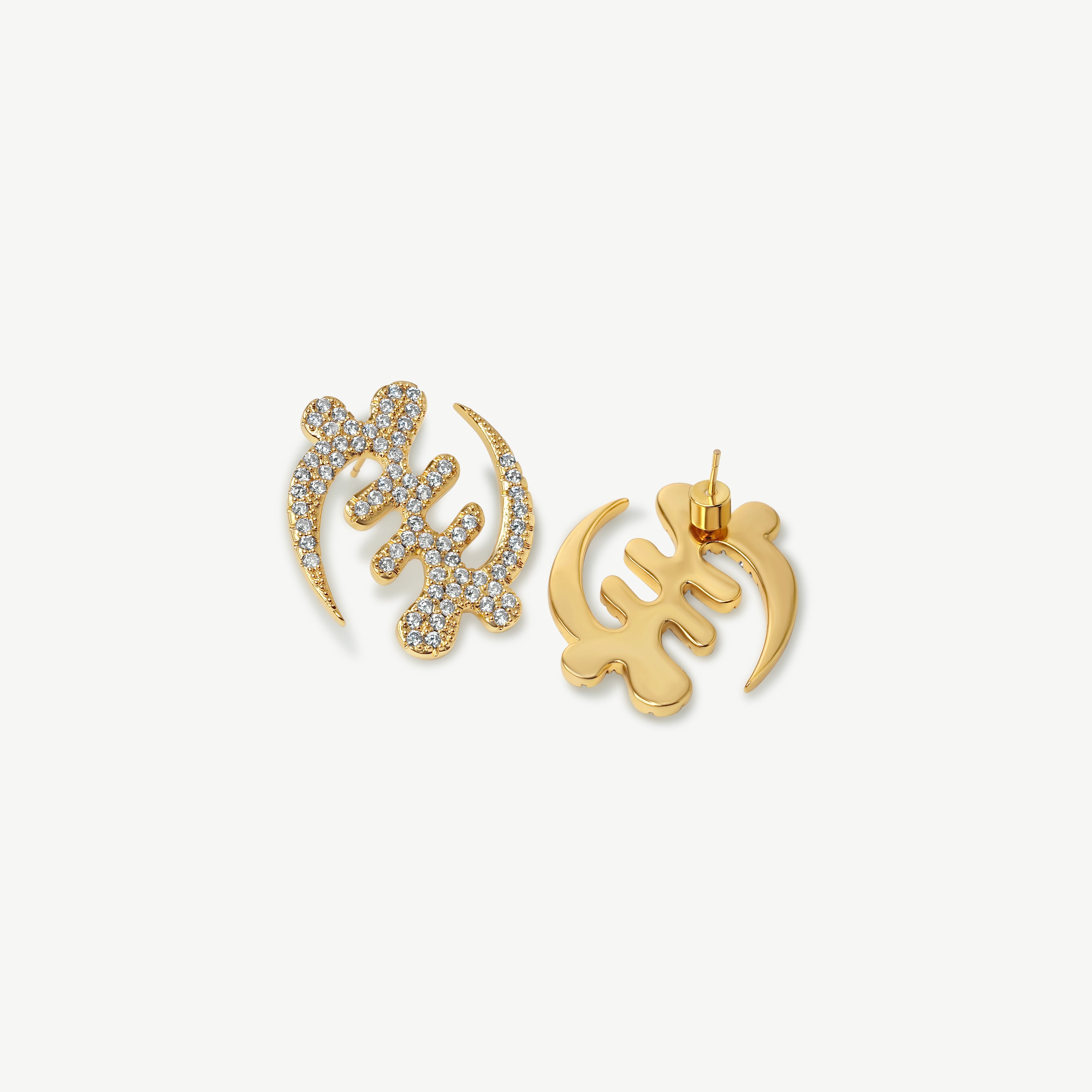 A high-resolution product shot of CASA London's 18k gold plated Gye Nyame Pavé oversized statement Earrings. The pair is shaped into the iconic Adinkra symbol, signifying the supremacy of God, and is intricately encrusted with shimmering pavé-set stones. Set against a minimalist white background, the design highlights the brand’s signature blend of cultural heritage and sophisticated modern luxury.