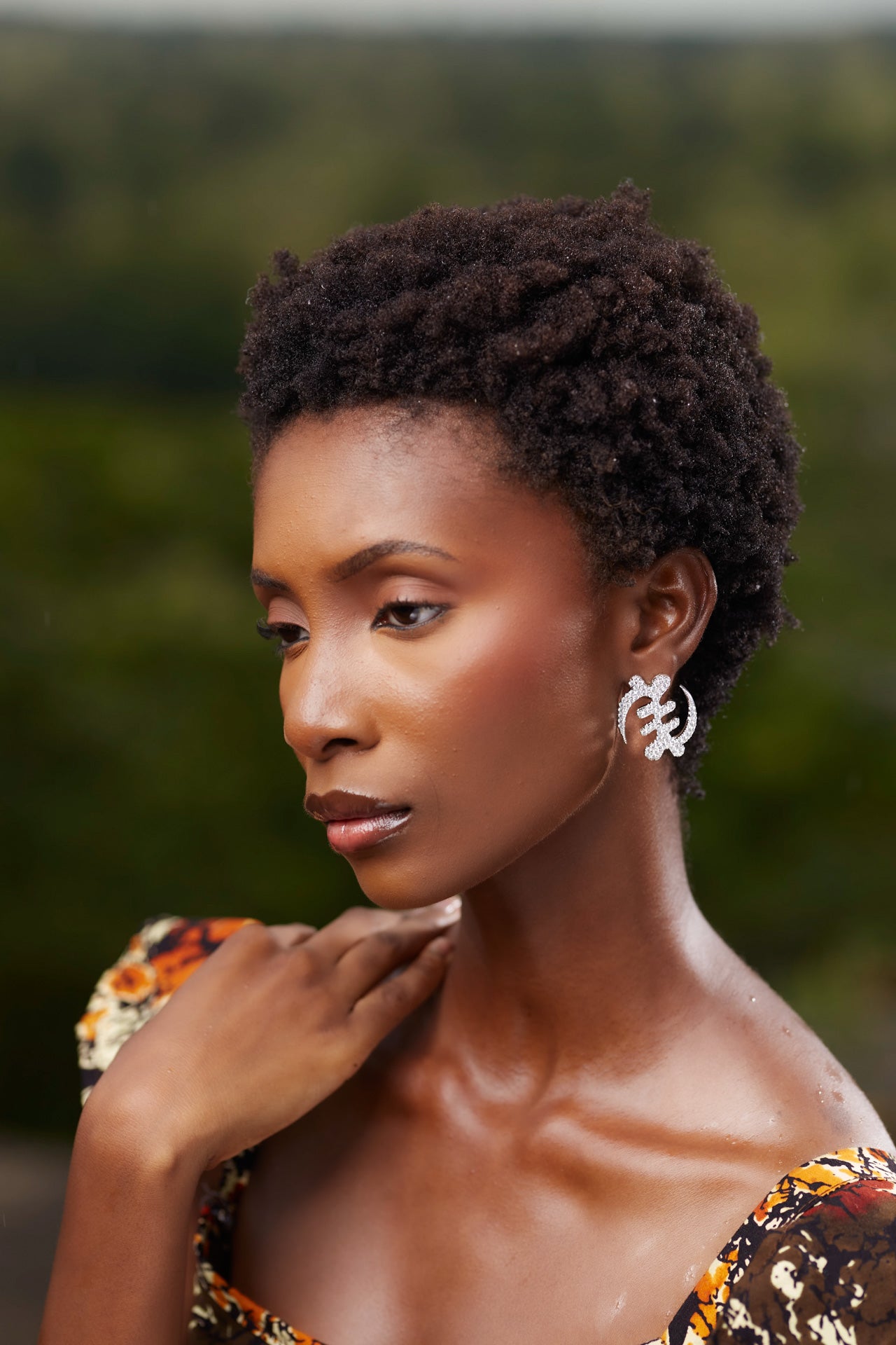 Model wearing large silver Gye Nyame Adinkra symbol earrings set with high-grade zircon stones, showcasing the traditional Ghanaian symbol of 'Except for God' in a shimmering pavé design.