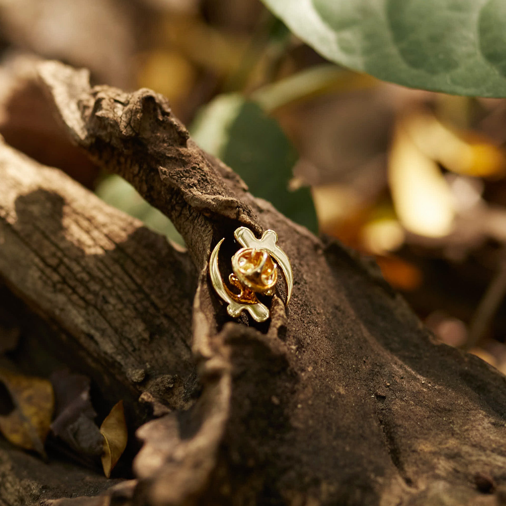 A product shot of CASA London's 18k gold plated Gye Nyame lapel pin. The pin is meticulously shaped into the iconic Adinkra symbol and encrusted with shimmering pavé-set stones. This display highlights the brand's commitment to superior craftsmanship and the fusion of cultural heritage with modern luxury.