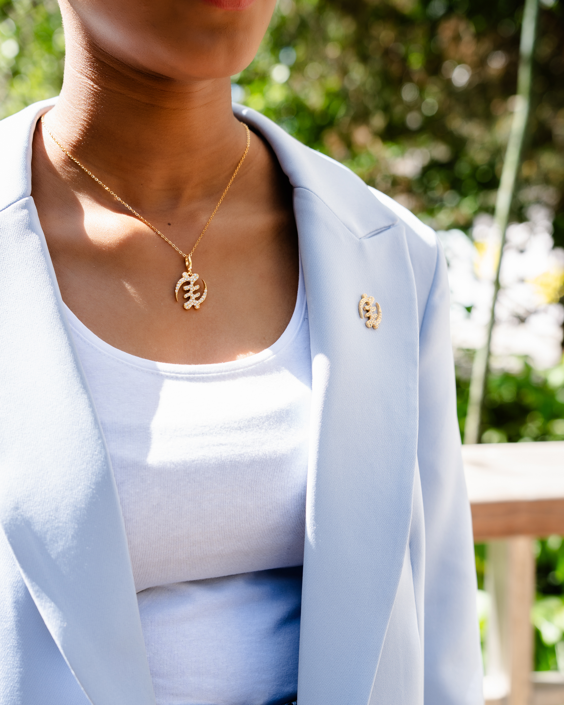 CASA LONDON Gye Nyame Pendant in 18ct gold plated — model wearing symbolizing the 'Supremacy of God', this pendant also adds cultural significance to your look, versatile and timeless, pair it with a chain or bracelet for a complete look.