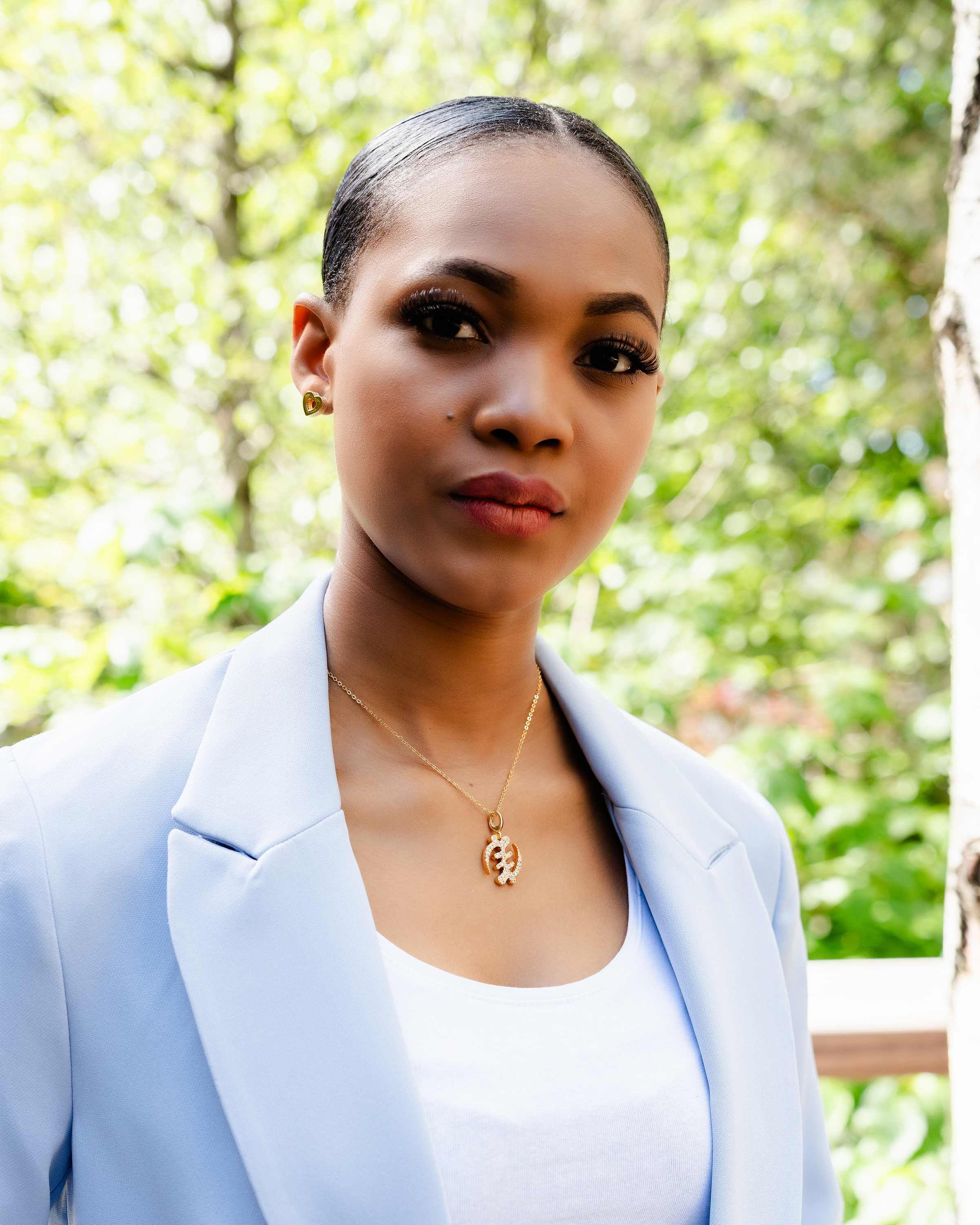 CASA LONDON Gye Nyame Pendant in 18ct gold plated — model wearing symbolizing the 'Supremacy of God', this pendant also adds cultural significance to your look, versatile and timeless, pair it with a chain or bracelet for a complete look.