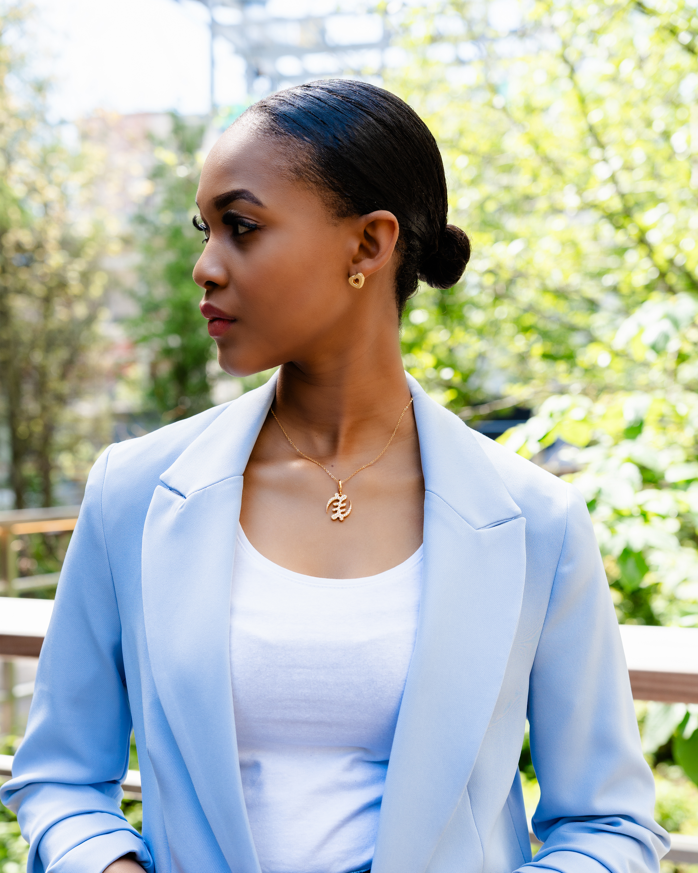 CASA LONDON Gye Nyame Pendant in 18ct gold plated — model wearing symbolizing the 'Supremacy of God', this pendant also adds cultural significance to your look, versatile and timeless, pair it with a chain or bracelet for a complete look.