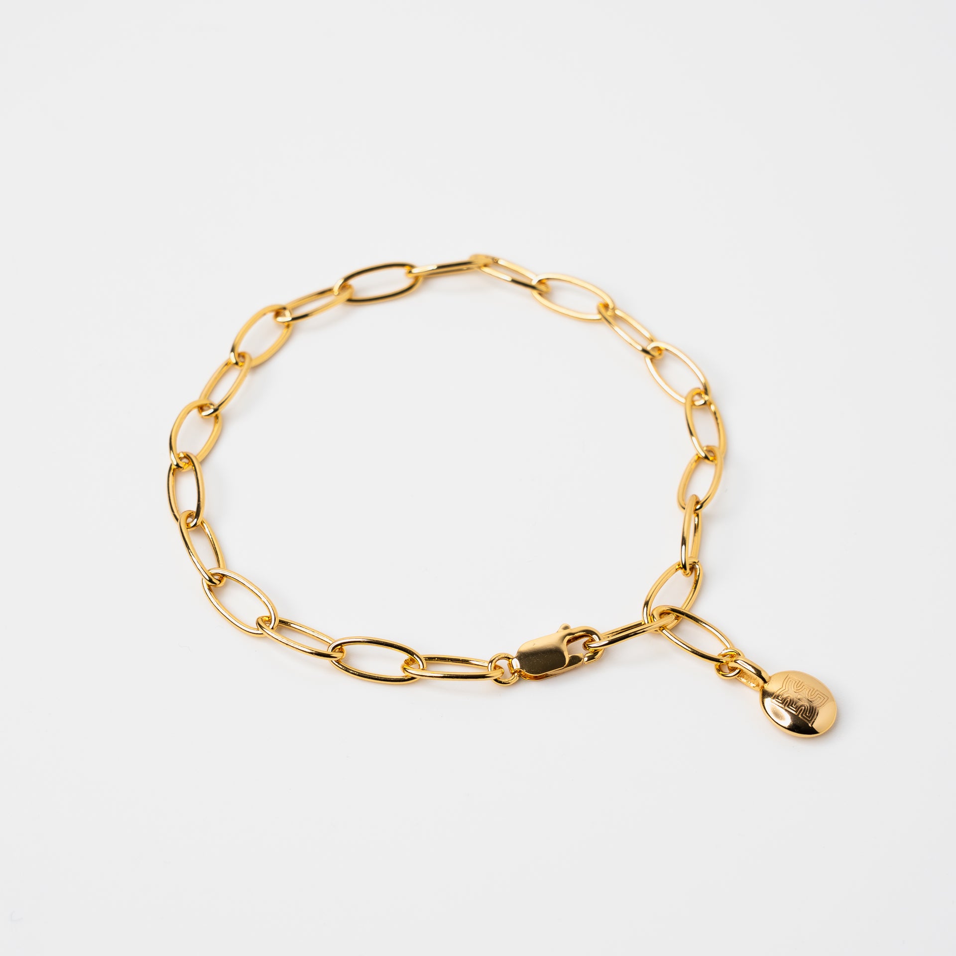 Gold vermeil link chain bracelet featuring a polished oval charm engraved with CASA London logomark engraved in tag, displayed on a clean white background.